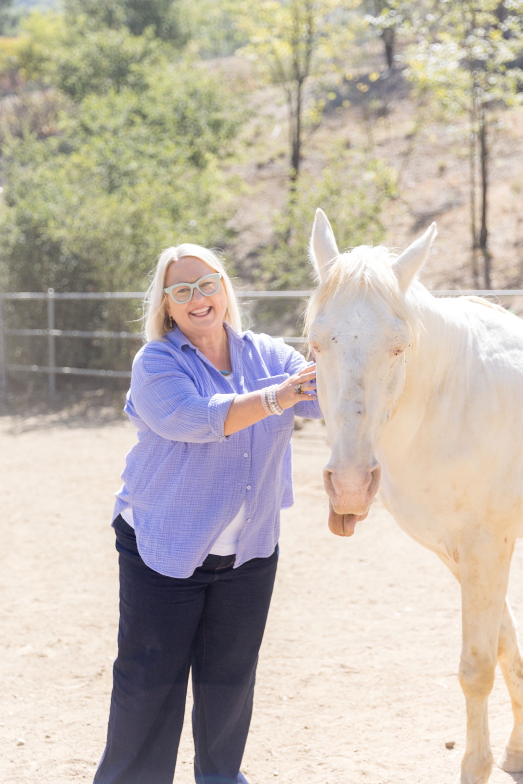 Angela laughing with a white horse at Shakti Ranch