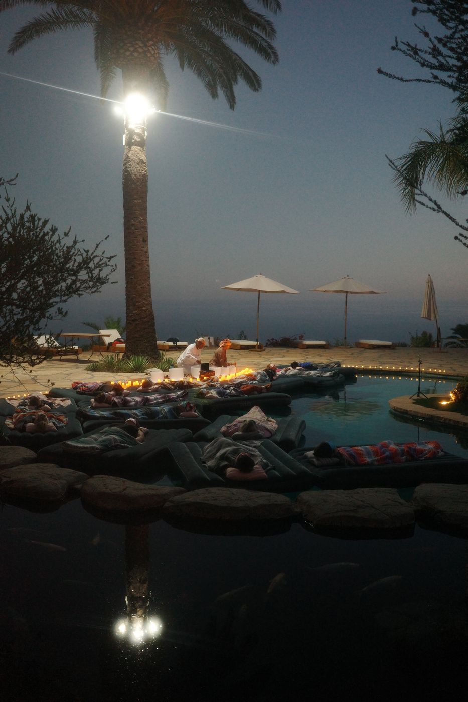 Lanterns glowing by the pool at dusk