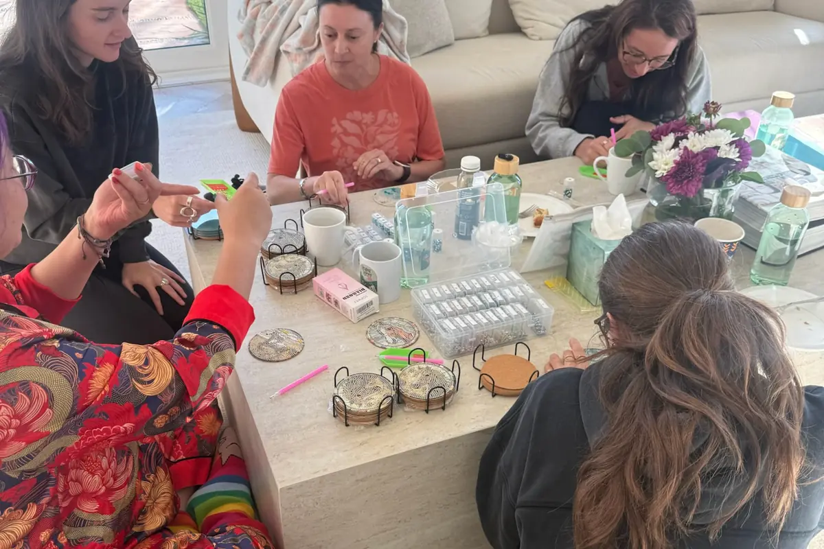 Women at the Healing with Horses retreat sitting around a coffee table, making diamond art coasters