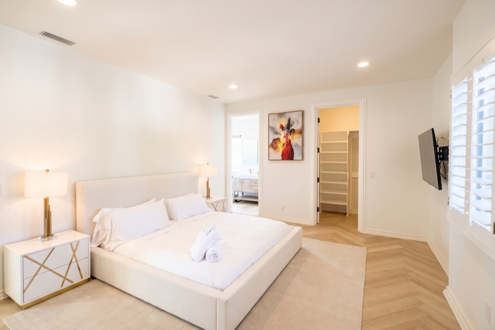 Shared room with a king bed, plantation shutters, an ensuite bath, and a walk-in closet