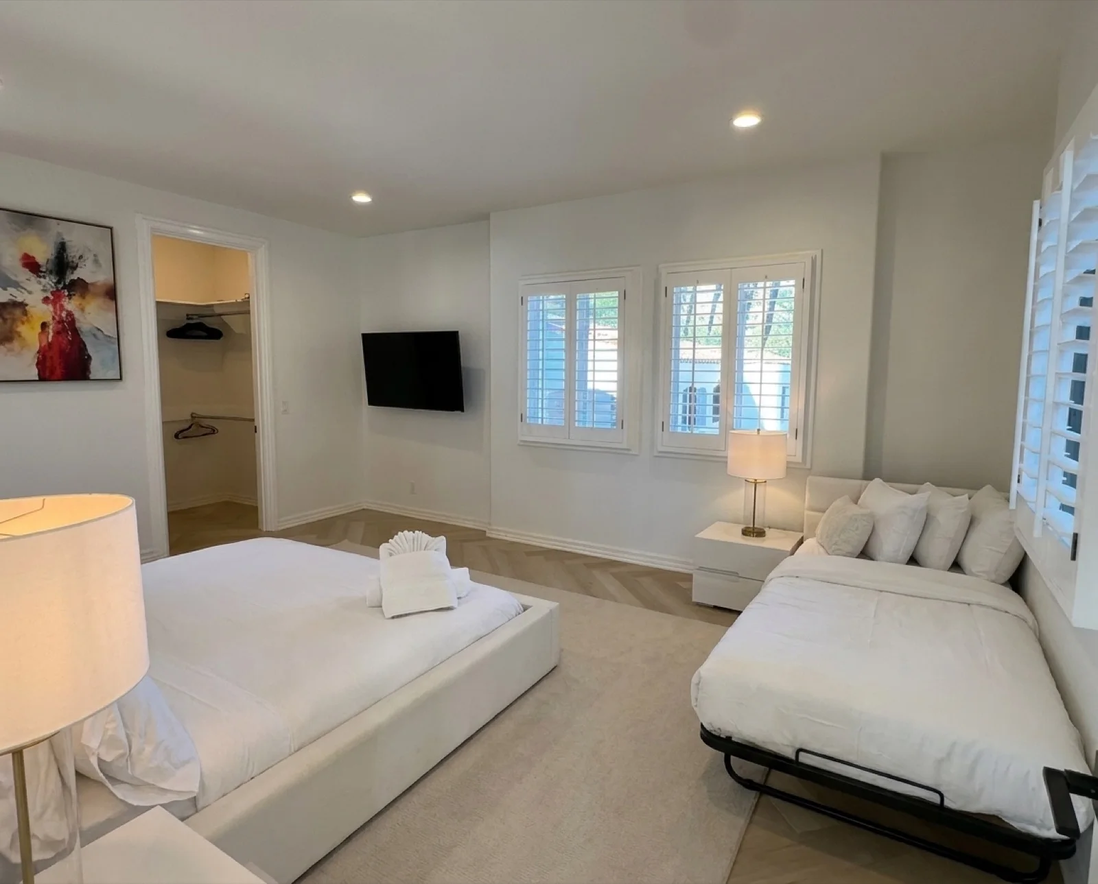 The Courtyard Room: a roomy shared bedroom, with a king bed, plantation shutters, and palm art