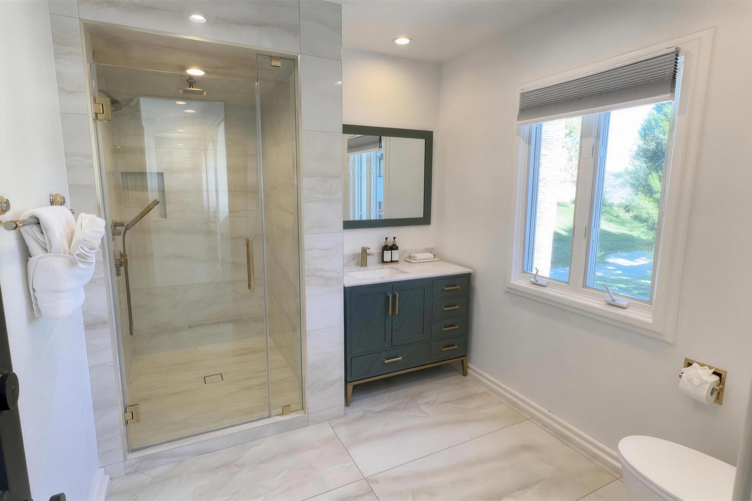The marble spa bath the two private rooms share, with a walk-in glass shower and garden window