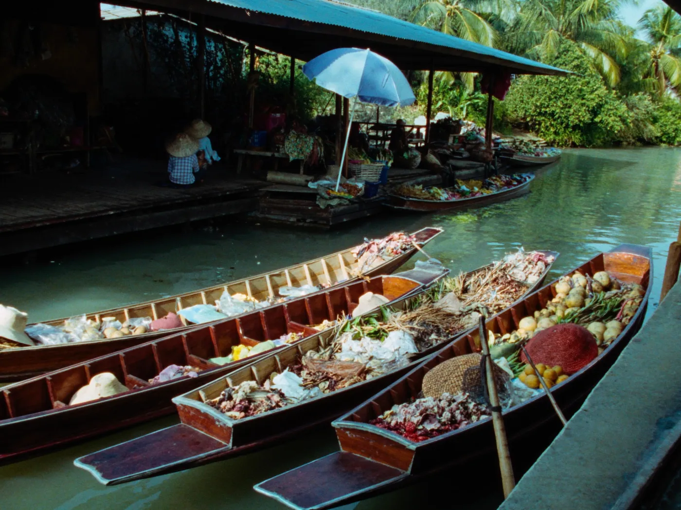 Wooden long-tail boats loaded with fruit and flowers at a Thai floating market