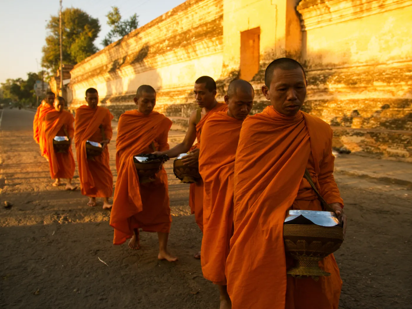 Monks in saffron robes walking at dawn almsgiving through the Chiang Mai old city