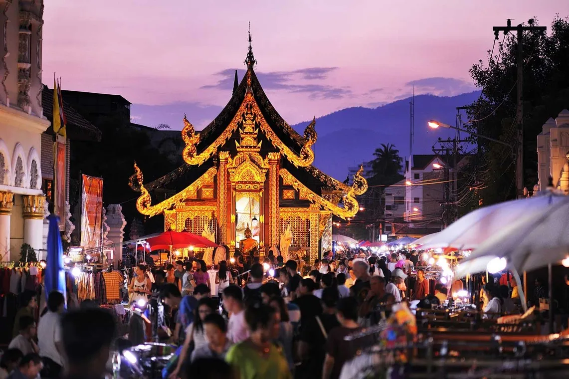 A gilded temple glowing over the Sunday night market at dusk